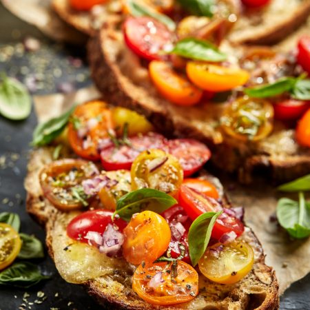 Tomato bruschetta with grilled homemade bread with cheese and fresh herbs